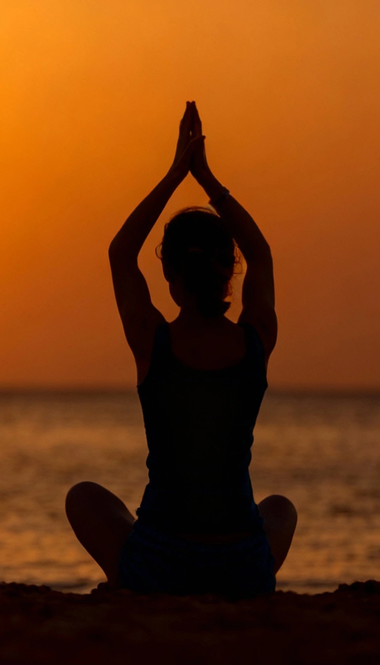A woman looking thoughtfully towards the sunset over the sea.