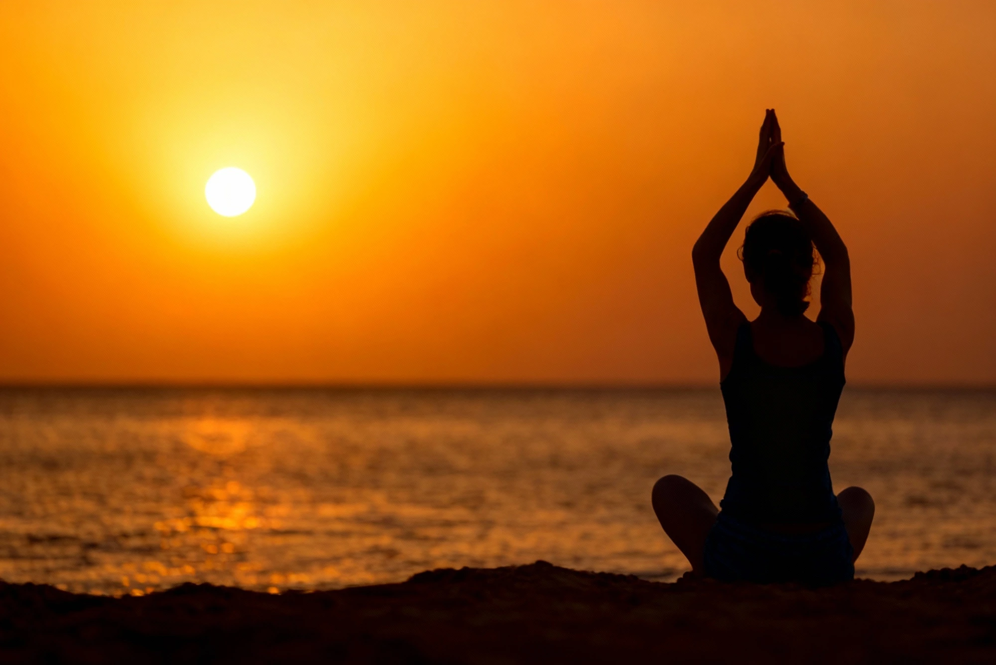 A woman looking thoughtfully towards the sunset over the sea.